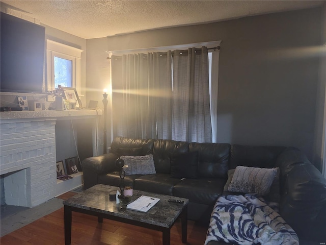 living room featuring a brick fireplace, hardwood / wood-style flooring, and a textured ceiling