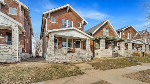 view of front of house featuring a porch, stone siding, and brick siding