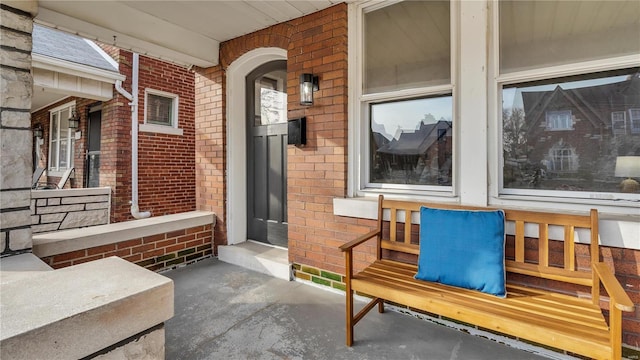 property entrance featuring covered porch and brick siding