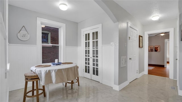 dining area with marble finish floor, arched walkways, and wainscoting