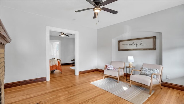 sitting room with ceiling fan, light wood-type flooring, and baseboards