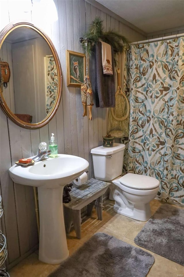 bathroom with tile patterned flooring, toilet, and wood walls