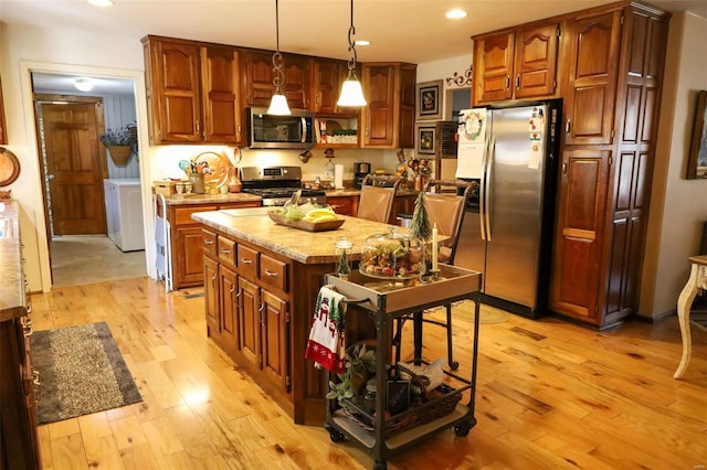 kitchen featuring pendant lighting, stainless steel appliances, a center island, and light wood-type flooring