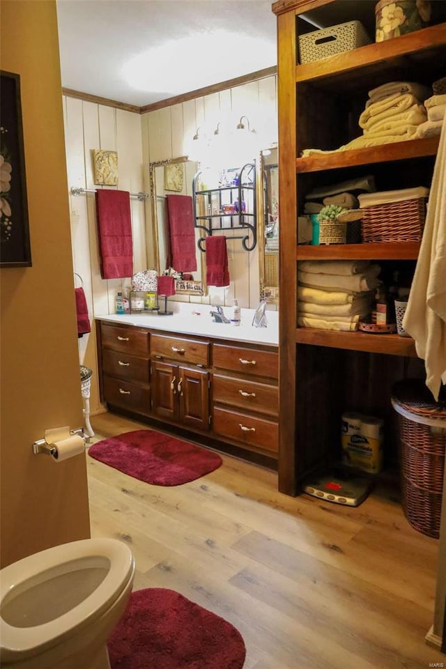 bathroom featuring vanity, ornamental molding, hardwood / wood-style floors, and toilet