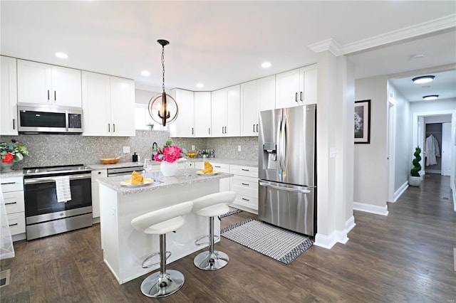 kitchen with dark wood-type flooring, backsplash, a center island, stainless steel appliances, and white cabinets