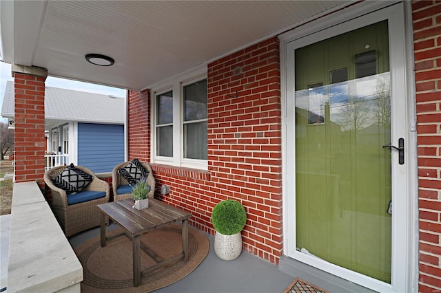 property entrance featuring covered porch and brick siding