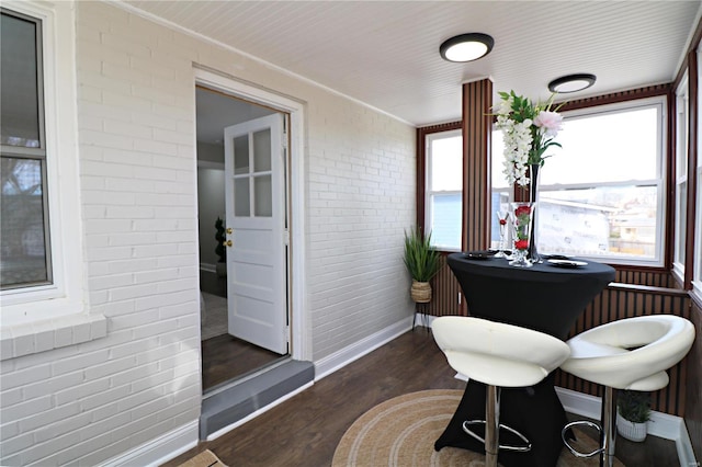 dining space with a wealth of natural light, dark wood-style floors, and brick wall