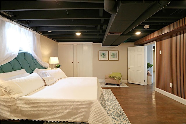 bedroom with wood finished floors, visible vents, a closet, and baseboards