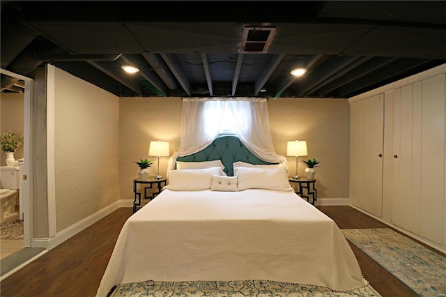 bedroom with dark wood-style floors, visible vents, and baseboards