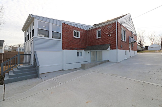 rear view of property with brick siding, a patio, and fence