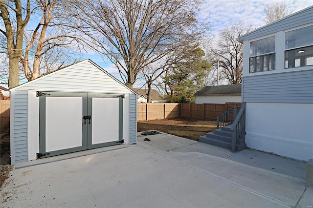 view of patio / terrace with a storage unit, a fenced backyard, and an outdoor structure