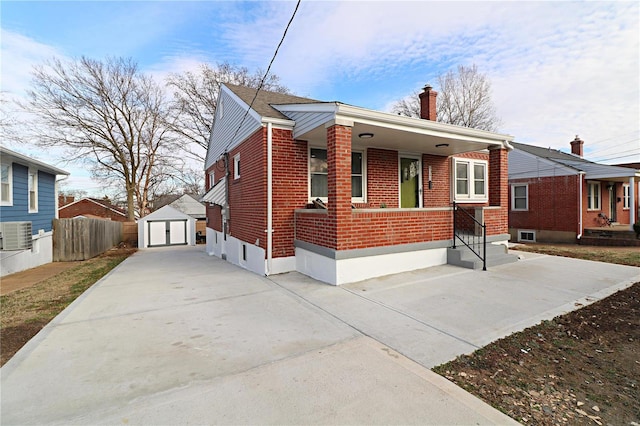 view of front of property with fence, concrete driveway, an outdoor structure, brick siding, and a chimney