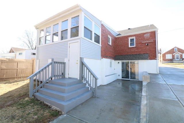 back of house featuring a patio, brick siding, and fence