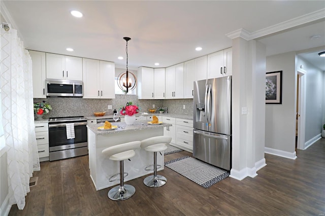 kitchen with a breakfast bar, backsplash, a kitchen island, dark wood finished floors, and stainless steel appliances