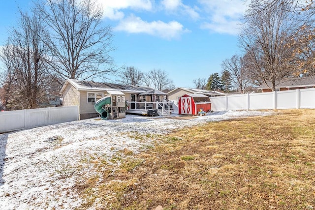 rear view of property featuring a wooden deck, a storage shed, and a lawn