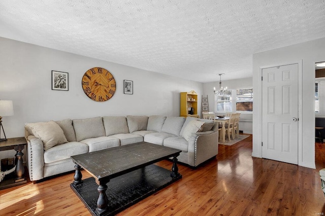 living room with wood-type flooring, a notable chandelier, and a textured ceiling