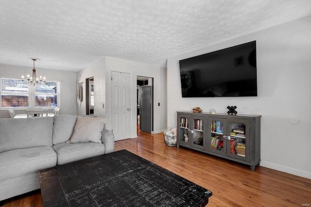 living room with an inviting chandelier, hardwood / wood-style floors, and a textured ceiling