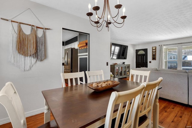 dining space featuring dark hardwood / wood-style flooring, a notable chandelier, and a textured ceiling