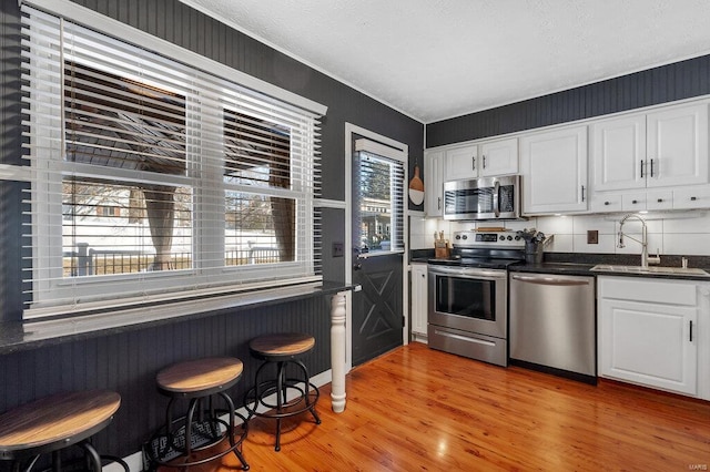 kitchen featuring stainless steel appliances, sink, white cabinets, and light hardwood / wood-style floors