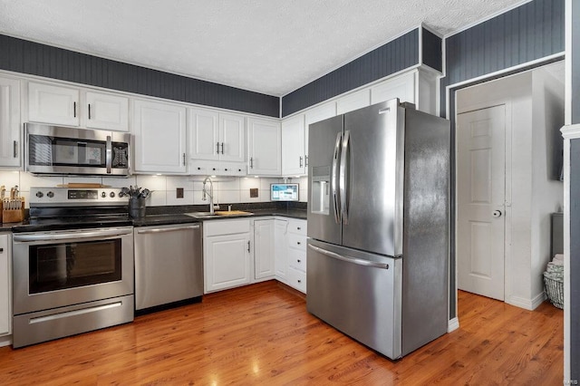 kitchen featuring white cabinetry, sink, light hardwood / wood-style floors, and appliances with stainless steel finishes