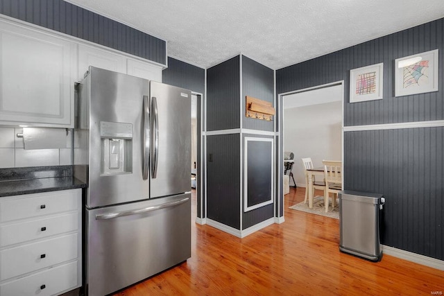 kitchen with white cabinets, stainless steel fridge, a textured ceiling, and light hardwood / wood-style flooring