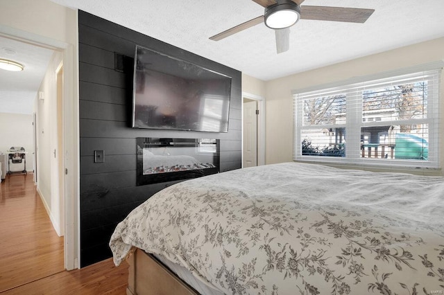 bedroom with hardwood / wood-style floors, a textured ceiling, and ceiling fan