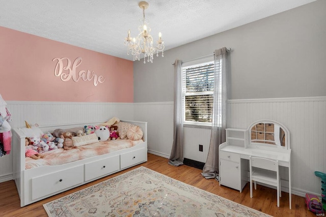 bedroom featuring an inviting chandelier, a textured ceiling, and light wood-type flooring