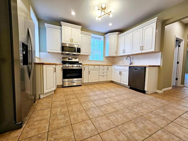 kitchen featuring appliances with stainless steel finishes, white cabinets, a sink, and light tile patterned flooring