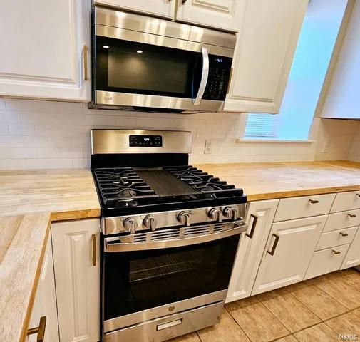 kitchen with appliances with stainless steel finishes, butcher block counters, and white cabinets