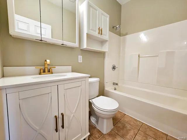 bathroom with toilet, vanity, tub / shower combination, and tile patterned floors