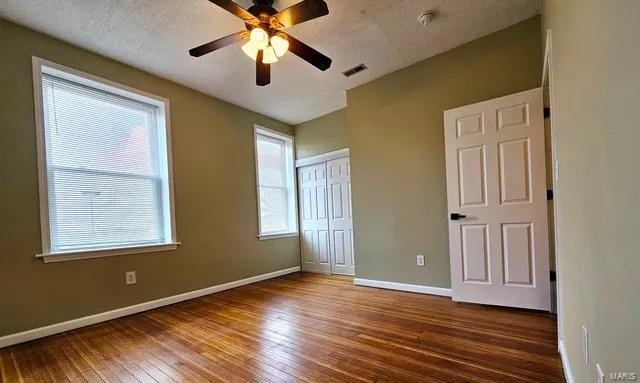 unfurnished bedroom featuring a closet, baseboards, a textured ceiling, and hardwood / wood-style floors