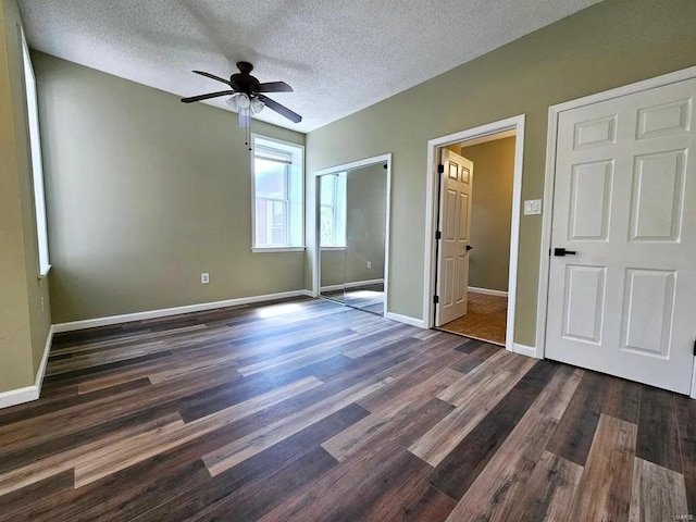 unfurnished bedroom featuring a closet, dark wood-type flooring, ceiling fan, a textured ceiling, and baseboards