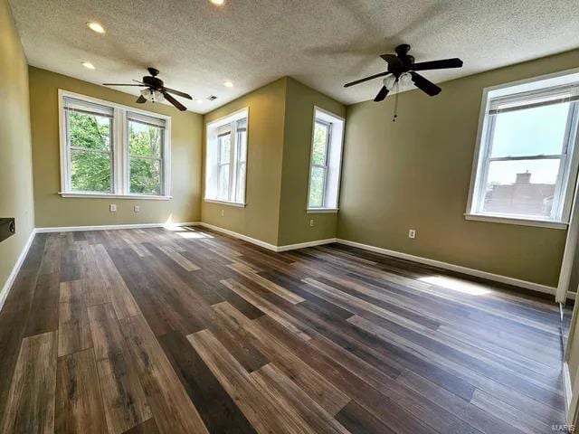 spare room featuring ceiling fan, baseboards, dark wood finished floors, and a textured ceiling