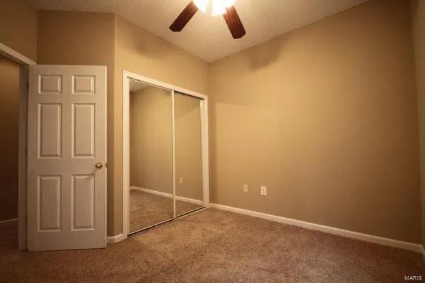 unfurnished bedroom featuring a ceiling fan, carpet, baseboards, and a closet