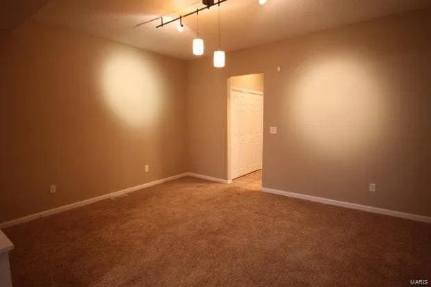 carpeted spare room with baseboards and track lighting