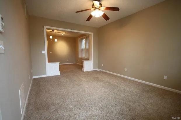 unfurnished room featuring carpet floors, a ceiling fan, visible vents, and baseboards