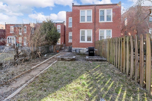 rear view of property featuring brick siding and a fenced backyard