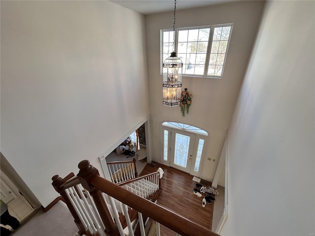 foyer with a towering ceiling, hardwood / wood-style floors, and a chandelier