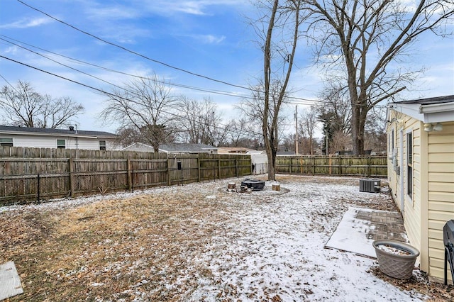 snowy yard featuring an outdoor fire pit and a fenced backyard