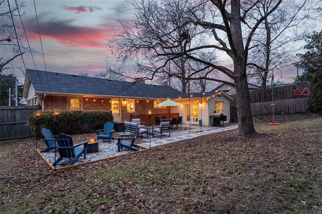 back house at dusk with an outdoor living space with a fire pit and a patio area