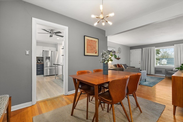 dining space featuring light wood-type flooring and ceiling fan with notable chandelier