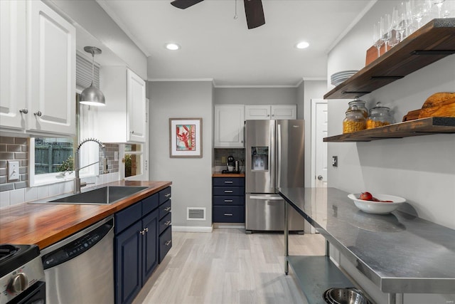 kitchen with stainless steel appliances, blue cabinets, sink, backsplash, and white cabinets