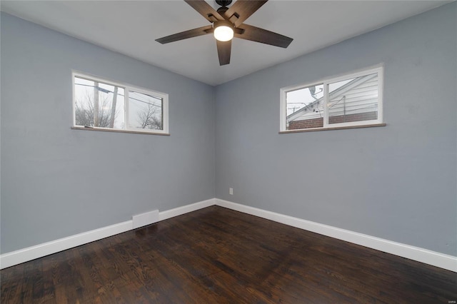 spare room featuring ceiling fan, dark hardwood / wood-style floors, and a healthy amount of sunlight