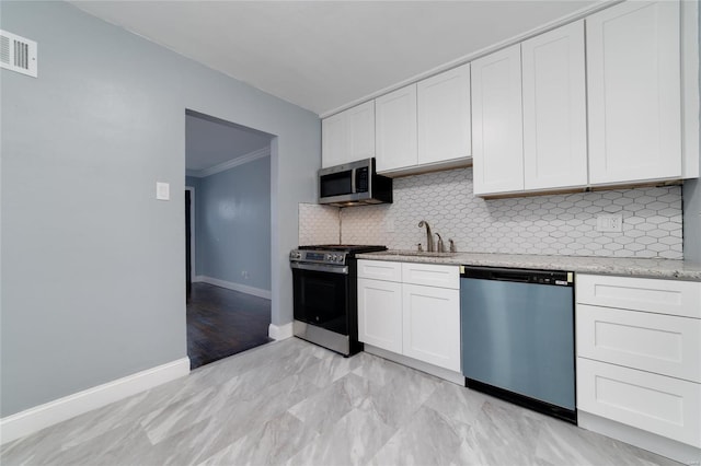 kitchen with baseboards, visible vents, appliances with stainless steel finishes, backsplash, and a sink