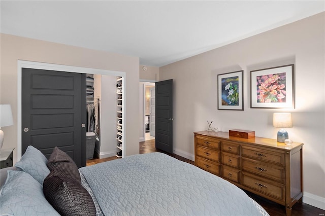 bedroom featuring baseboards, dark wood-type flooring, and a closet