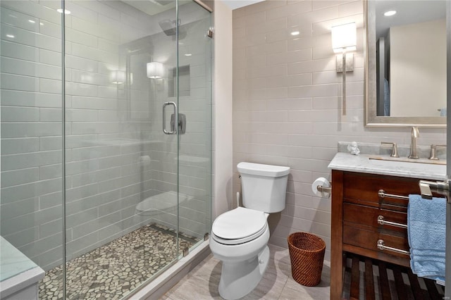 full bath with tile walls, toilet, a stall shower, vanity, and tile patterned floors