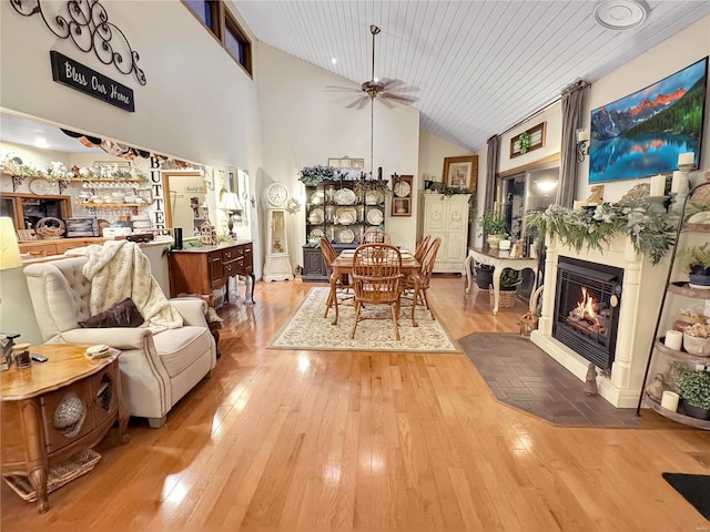 dining room featuring ceiling fan, a towering ceiling, wood ceiling, and light hardwood / wood-style floors