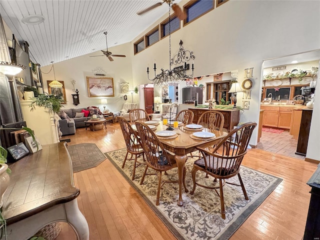 dining room featuring ceiling fan, high vaulted ceiling, and light hardwood / wood-style flooring