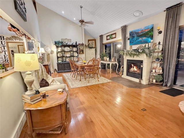 living room with high vaulted ceiling, hardwood / wood-style flooring, ceiling fan, a high end fireplace, and wooden ceiling