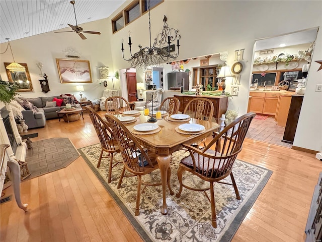 dining room featuring high vaulted ceiling, ceiling fan, and light wood-type flooring